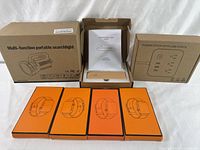 Photo showing the boxed multi-function portable searchlight, magnetic wooden night lamp, power strip with USB ports, and four orange-boxed smartwatch wristbands arranged neatly