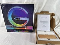 Photo showing smart light sound machine box with product design image and packaging, alongside opened box of wooden night lamp with instruction manual and components.