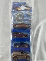 Full view of sealed Hot Wheels 4-pack on card, showing all four cars stacked vertically inside blister packaging.