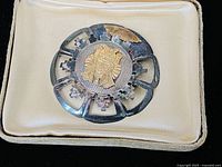 Front view of antique large brooch showing sterling silver and gold Native face centerpiece with patina