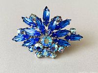 Front view of vintage brooch showing blue marquise-shaped rhinestones and smaller AB round rhinestones in silver-tone setting.