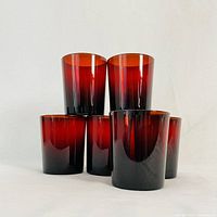Six ruby glass cups arranged in a pyramid shape with three at the base and one on top showing their color and shape