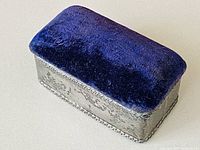 Top and sides view of the rectangular jewelry box with deep purple velvet top and ornate silver sides with rope border detail.
