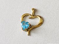 Front view of vintage 10K gold heart-shaped pendant with blue heart-shaped gemstone.