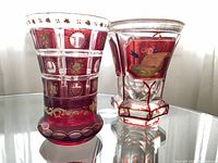 Two antique crystal vases displayed on glass table, showing shape, color, and decoration