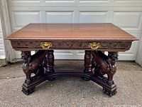 Front view of entire desk showing top surface, carved apron, griffin supports and brass hardware