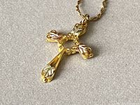 Close-up of cross pendant showing tri-color leaf motif in yellow, white and rose gold