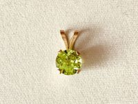 Top-down view of the vintage peridot pendant showcasing the round faceted lime green peridot gemstone set in 10K gold claw setting with dual bail.