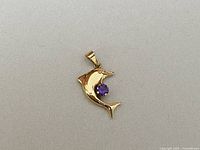 Front view of the yellow gold dolphin pendant showing amethyst gemstone.
