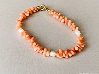 Full view of the vintage pink coral and pearl bracelet showing coral chips, pearl beads, and clasp.