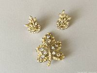 Front view of the brooch and earrings laid on a flat surface showing the set details