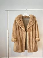 Front view of the beige mink fur coat on a hanger showing collar and cuffs