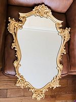Overhead shot of entire mirror on leather surface showing full ornate frame and mirror glass