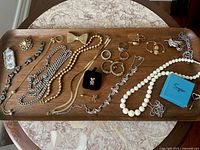 Full view of assorted antique and vintage jewelry on wooden tray including necklaces, bracelets, earrings, rings, brooches, and storage box