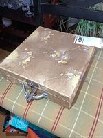 Closed vintage floral patterned box with latch, containing goblets inside.
