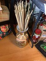 Full view of 18-inch tall porcelain Asian vase with faux pussy willow stems, placed on wooden floor near chair and shelves