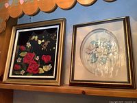 Photo showing 3D floral clock with red roses and adjacent 3D floral art piece in frames hanging on wall.