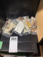 Fifteen small collectible figures in original plastic bags, each with an informational card, displayed on a shelving unit.