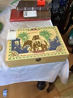 Closed wooden box with vintage elephant design, placed on table with background items.