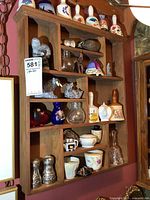 Front view of the entire wooden display shelf with various small collectibles arranged in compartments.