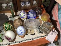 All eggs, candy dish, paperweights and inkwell arranged on cloth