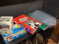 Three hockey card boxes placed on a shelf with plastic sleeves beside them, showing the variety included in the lot.