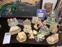 View of entire lot showing numerous resin miniature cottages and bear figurines arranged on a dark surface.