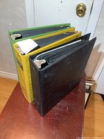 Three 3-ring binders (black, yellow, green) closed view