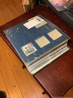 Blue album filled with postcards shown closed on a wooden table