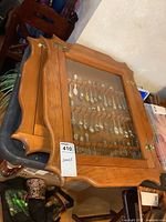 Full view of two stacked wooden spoon racks with glass front doors showing mounted spoons inside.