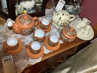 Clay teapot set including teapot, creamer, sugar bowl, cups and saucers, plus white ceramic miniature teapots set on tray