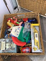 Top view of a basket filled with assorted small and medium die cast cars, collectible toys, boxed Star Wars Yoda figure, Giant Tiger Custom Hauler truck in box, and fabric marble pouches.