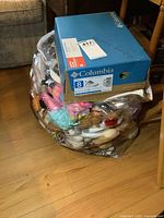 Photo showing a Columbia shoebox on top of a large plastic bag filled with assorted plush toys