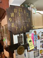 Front view of vintage oak mission style wall clock showing rectangular wooden clock face with gold Arabic numerals and pendulum below.