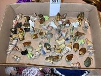 Top down photo showing a wide array of small figurines including nursery rhyme characters and animals arranged inside a cardboard tray.