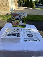 Photo of the Air Hogs Hyper Stunt Drone in blister packaging with box, remote, accessories, and instruction sheet on white tablecloth.