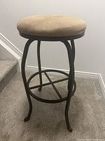 Full view of stool showing black metal frame, beige seat, height and design