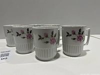 Front view of six matching porcelain mugs showing floral design and ribbed bases