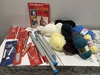 Overview of yarn, knitting needles, booklet on table
