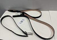 Top view of two belts showing buckles, tags and overall length