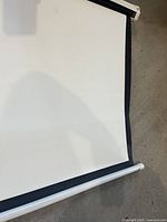 Screen partially unrolled showing white viewing surface with black border