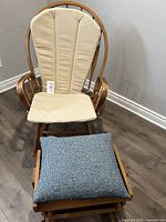 Front view of rocking chair with beige cushions and gliding footstool with blue cushion