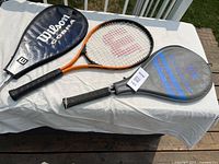 All three rackets with covers displayed on table outdoors