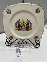 Front of square commemorative plate on stand showing portraits and flags