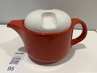 Side view of red teapot with white lid