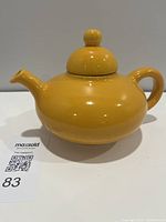 Full side view of mustard yellow teapot with handle and spout