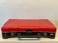 Closed red enamel lid, front control panel with two knobs, push-button ignition and Coleman logo