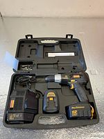 Open black plastic carrying case containing Craftsman 12V cordless drill, rechargeable battery, battery charger, and space for accessories.