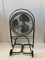 Front view of large Emerson Electric industrial floor fan on metal stand with wheels, showing protective grille and corded power source.