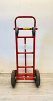Front view of red Milwaukee hand truck upright, showing frame and wheels.